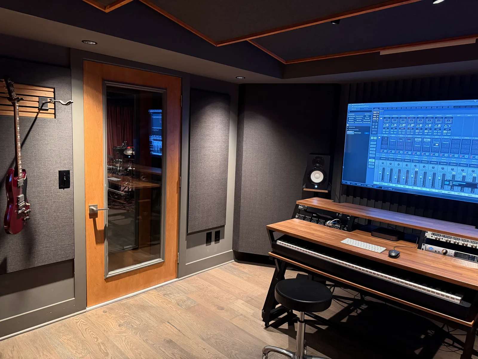 The control room from the left. Window into the live room, guitar on the wall