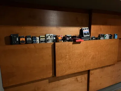 Pedal collection lined up along the wood paneling in the live room